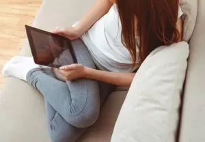 girl curled up on couch with ipad pap smear and cervical screening test