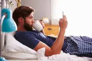 bloke smartphone in bed how to see a GP online
