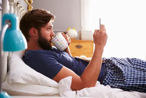 bloke smartphone in bed online doctor