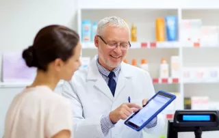 Pharmacist and female customer with digital prescription on tablet computer screen.