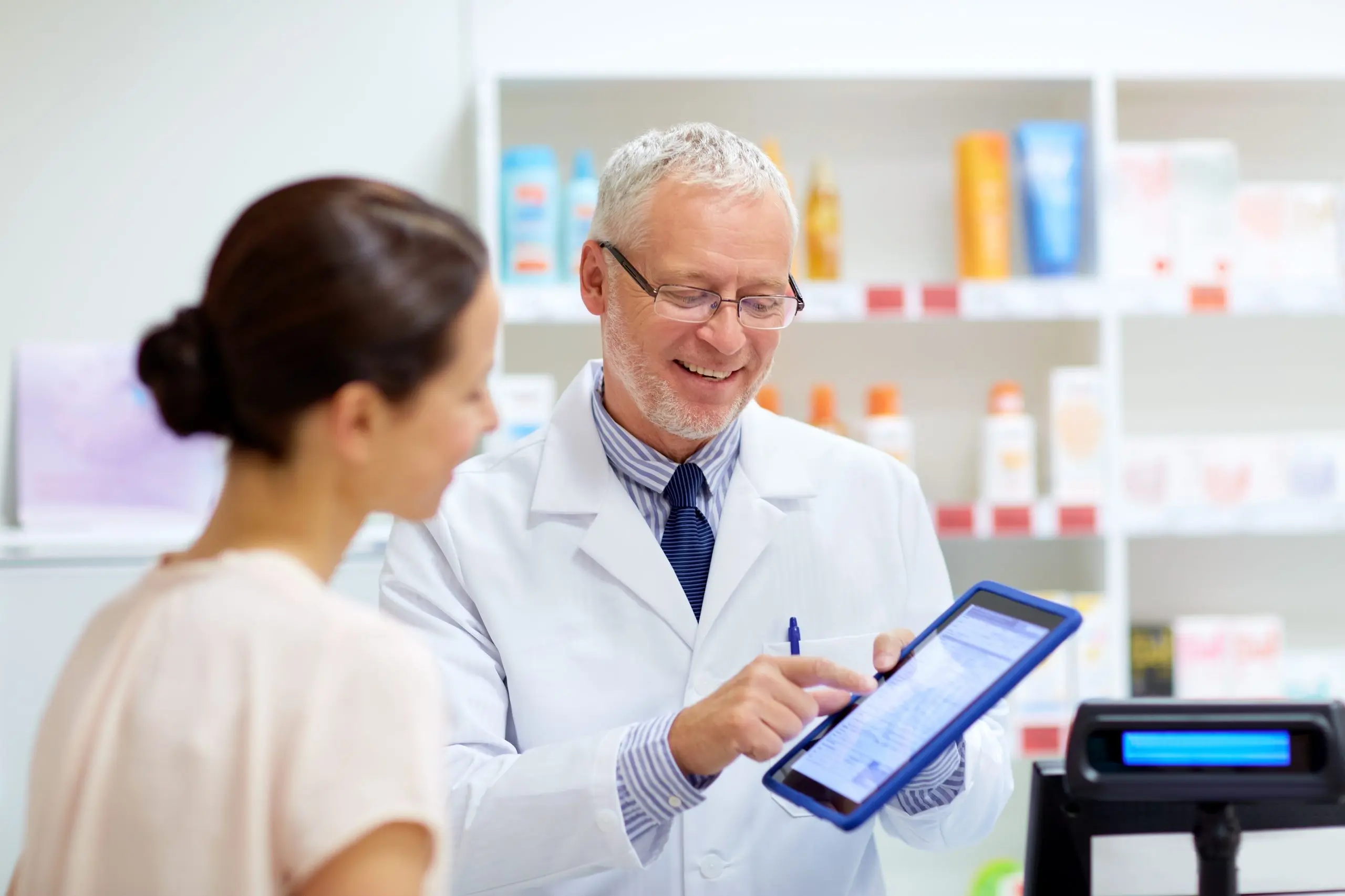 Pharmacist and female customer with digital prescription on tablet computer screen.