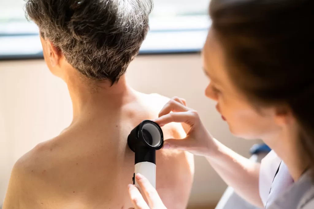 Doctor checking for non-melanoma skin cancers on a man's back