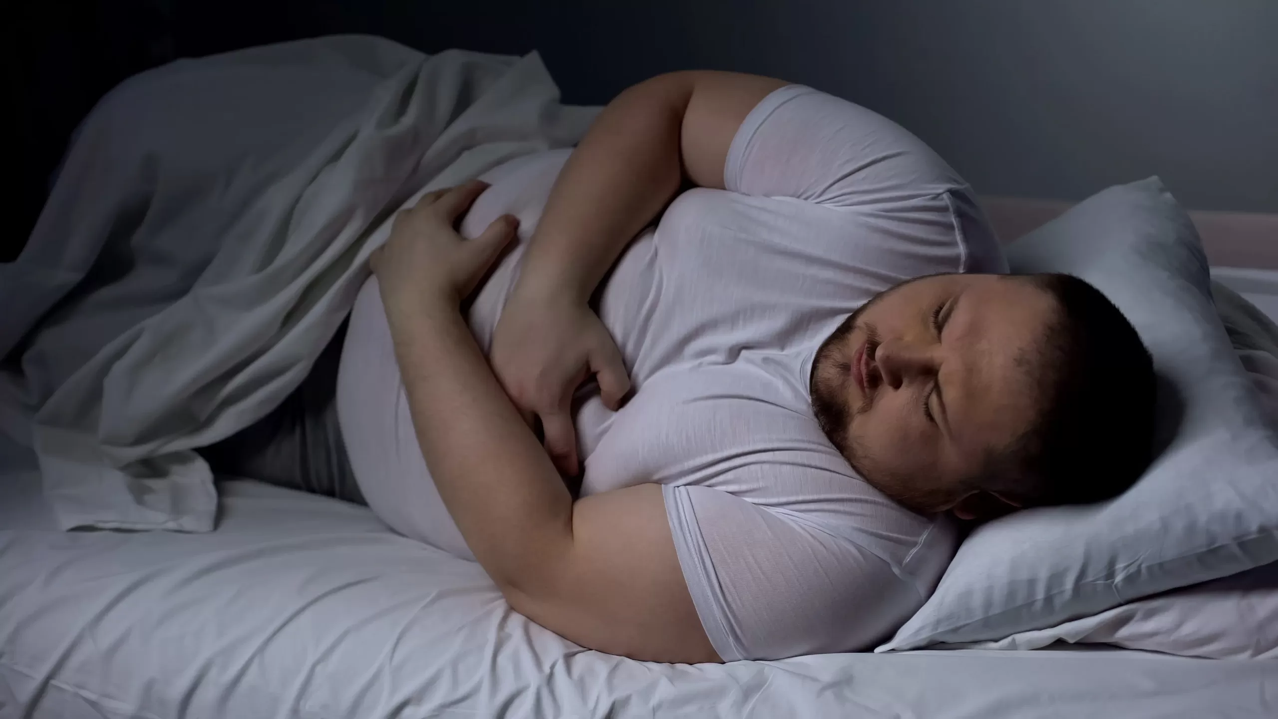 Overweight man suffering from fatty liver disease, showing liver discomfort at nigh