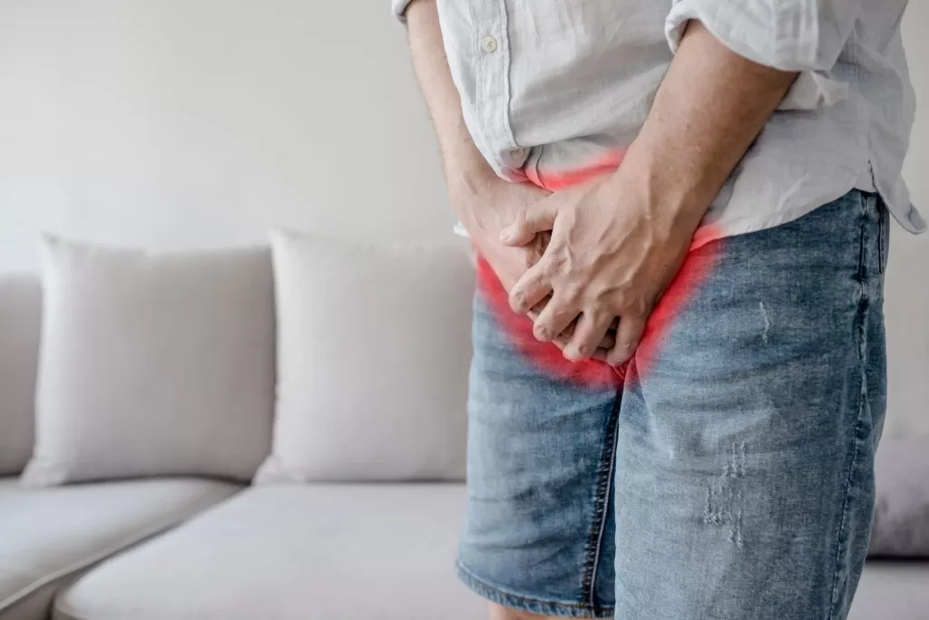 Male suffering from osteitis pubis holds his genitals with pain
