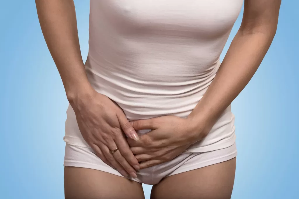 Young woman with hands pressing lower abdomen as a symptom of osteitis pubis