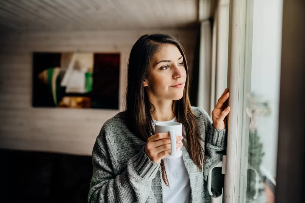 Young-woman-gazing-through-to-the-window-avoiding-social-contact-scaled Young woman gazing through to the window avoiding social contact