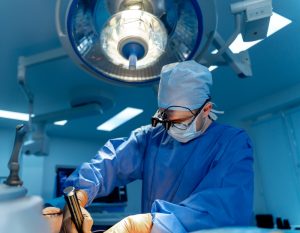 Surgeon,At,Work,In,Modern,Or.,A,Surgeon,Focuses,On Young female doctor in white medical uniform with stethoscope using laptop for online consultation with a patient