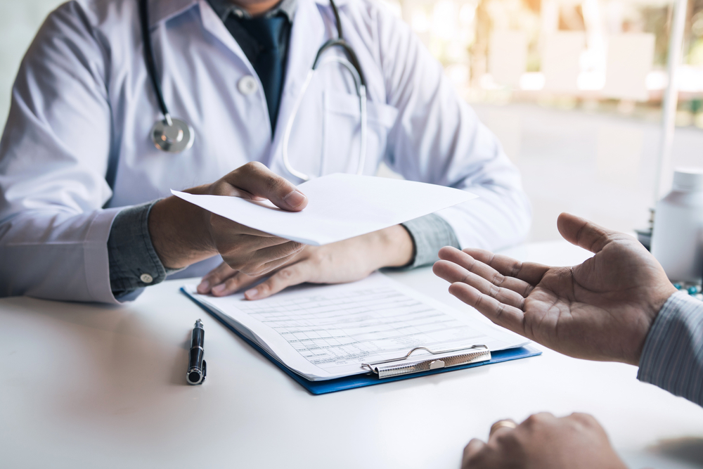 doctor handing a medical certificate to a patient