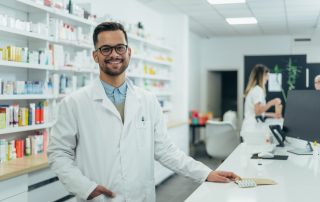 a smiling male pharmacist in the dispensary