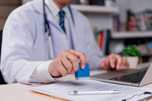 Doctor,Is,Stamping,An,Important,Medical,Document,,Indicating,The,Confirmation Sick girl wrapped in scarf holding tissue at face and consulting doctor online on video call